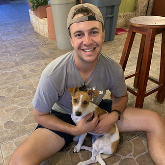 Man holding small dog indoors, both smiling at camera in home setting.
