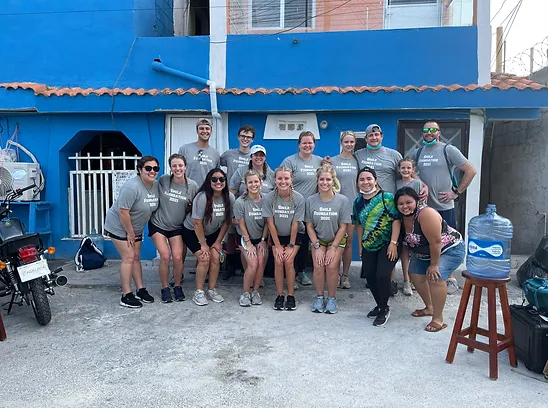 Large group of Smile Foundation volunteers posing together outside blue building headquarters.
