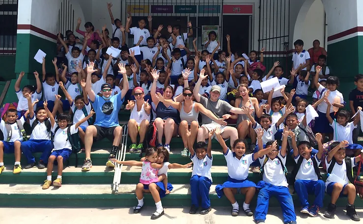 Large group of children and volunteers sitting together on outdoor bleachers at community event.